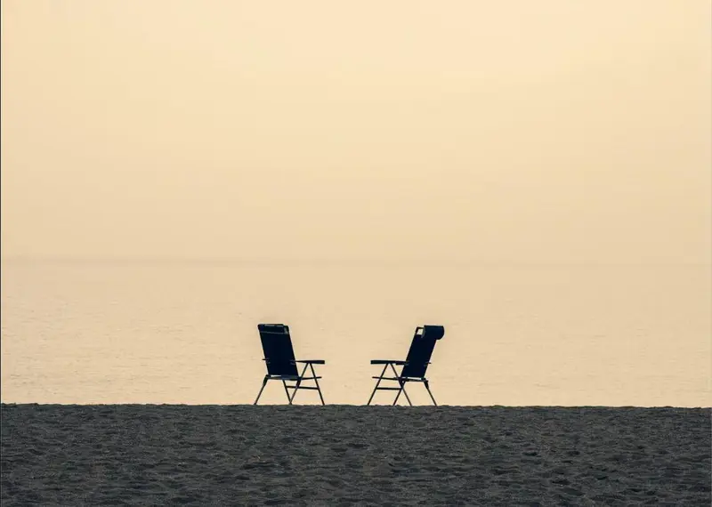 Twee lege stoelen tegenover elkaar aan zee, symbool voor een rustig coachgesprek